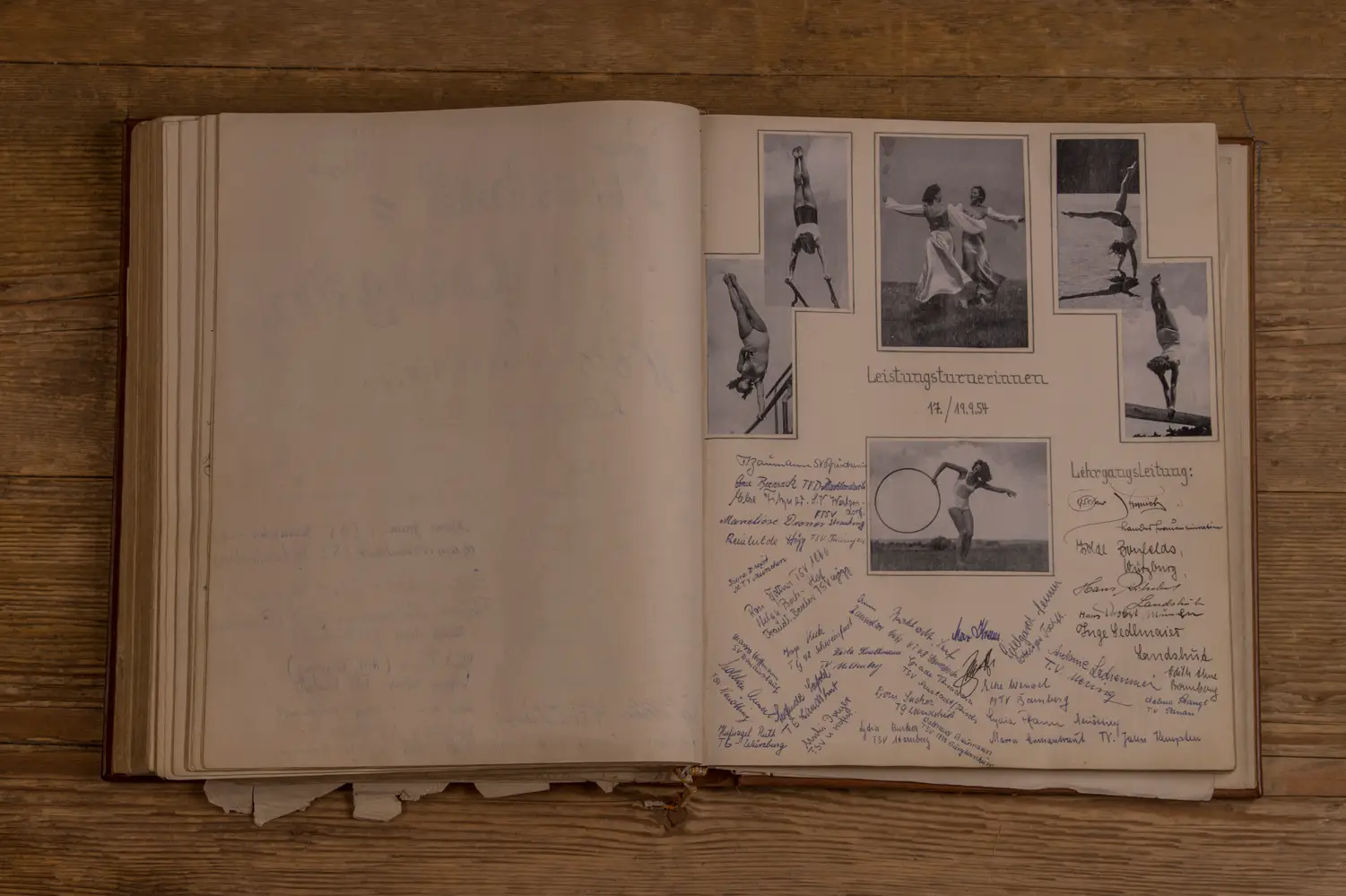 Aufgeschlagenes Buch auf einem Holztisch, zeigt eine Seite mit Schwarz-Weiß-Fotografien von Turnerinnen in verschiedenen Posen und handschriftlichen Notizen und Unterschriften darunter. Oben steht "Leistungsturnerinnen 17./19.9.34". Rechts befinden sich weitere handschriftliche Bemerkungen und der Titel "Lehrgangsleitung".