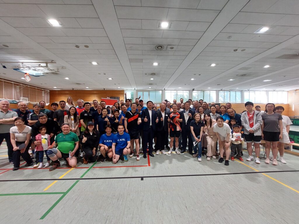 Eine Gruppe von personen in Sportkleidung steht in einer großen Sporthalle an der Sportschule Oberhaching für ein Gruppenfoto