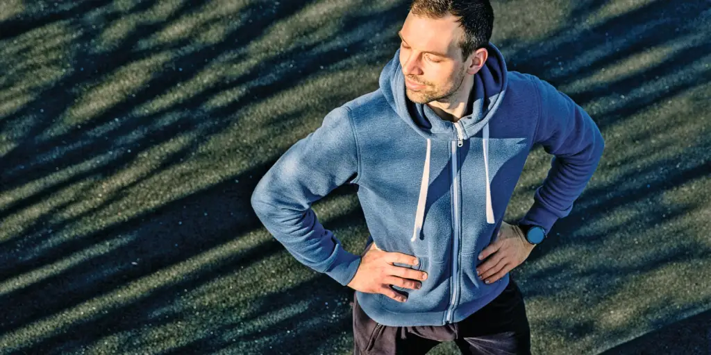 Sportlicher Mann (Prof. Hermann) auf einer Laufbahn während einer Trainingspause – Symbolbild für Stressmanagement, mentale Gesundheit und aktive Erholung.