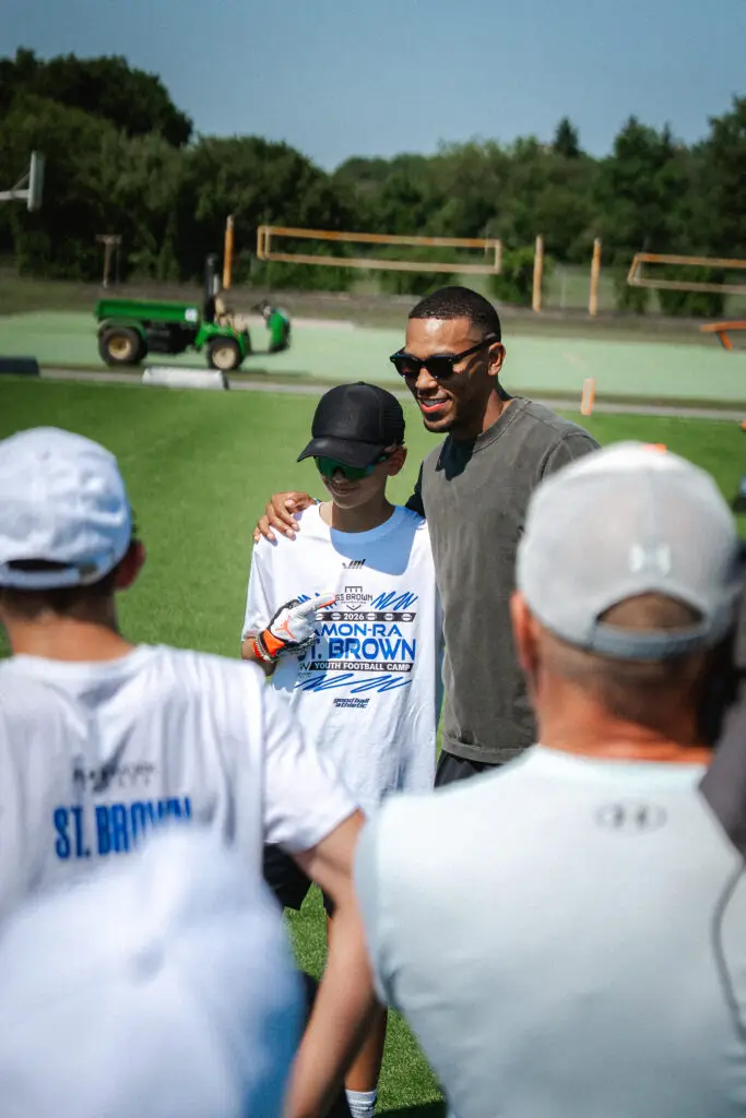 Camp-Teilnehmer lässt sich während eines American-Football-Camps mit NFL Star Amon Ra St. Brown fotografieren