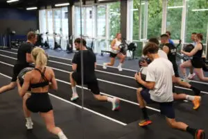 Gruppe absolviert Ausfallschritte mit Wallballs beim HYROX-Training im S.P.O. Club der Sportschule Oberhaching.