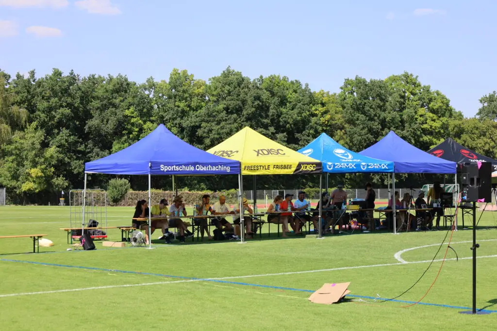 Bildergalerie vom Frisbee Festival M&uuml;nchen an der Sportschule Oberhaching mit Spielszenen auf dem Sportplatz und in der Halle, Turnierst&auml;nden, Zuschauerinnen und Zuschauern sowie verschiedenen Frisbee-Disziplinen wie Disc Golf, Ultimate Frisbee und Freestyle.