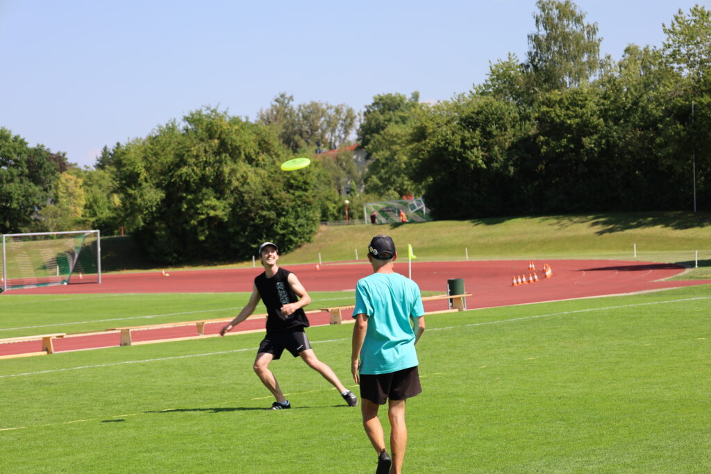 Bildergalerie vom Frisbee Festival M&uuml;nchen an der Sportschule Oberhaching mit Spielszenen auf dem Sportplatz und in der Halle, Turnierst&auml;nden, Zuschauerinnen und Zuschauern sowie verschiedenen Frisbee-Disziplinen wie Disc Golf, Ultimate Frisbee und Freestyle.