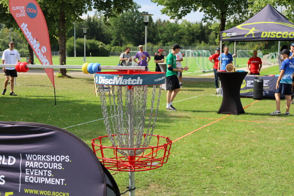 Bildergalerie vom Frisbee Festival M&uuml;nchen an der Sportschule Oberhaching mit Spielszenen auf dem Sportplatz und in der Halle, Turnierst&auml;nden, Zuschauerinnen und Zuschauern sowie verschiedenen Frisbee-Disziplinen wie Disc Golf, Ultimate Frisbee und Freestyle.