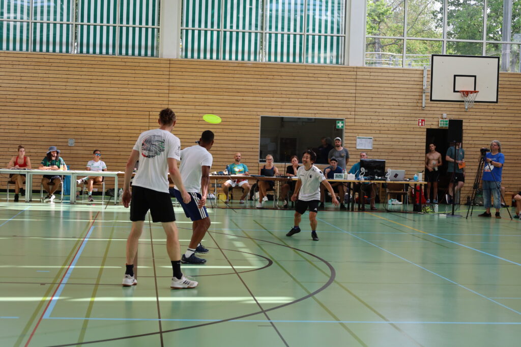 Bildergalerie vom Frisbee Festival M&uuml;nchen an der Sportschule Oberhaching mit Spielszenen auf dem Sportplatz und in der Halle, Turnierst&auml;nden, Zuschauerinnen und Zuschauern sowie verschiedenen Frisbee-Disziplinen wie Disc Golf, Ultimate Frisbee und Freestyle.
