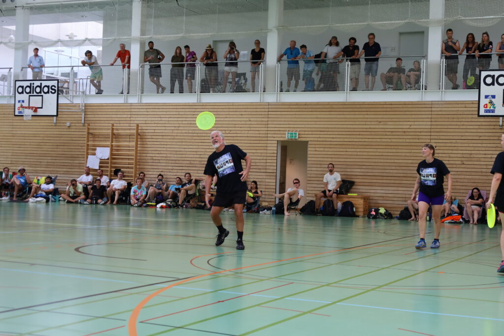 Bildergalerie vom Frisbee Festival M&uuml;nchen an der Sportschule Oberhaching mit Spielszenen auf dem Sportplatz und in der Halle, Turnierst&auml;nden, Zuschauerinnen und Zuschauern sowie verschiedenen Frisbee-Disziplinen wie Disc Golf, Ultimate Frisbee und Freestyle.
