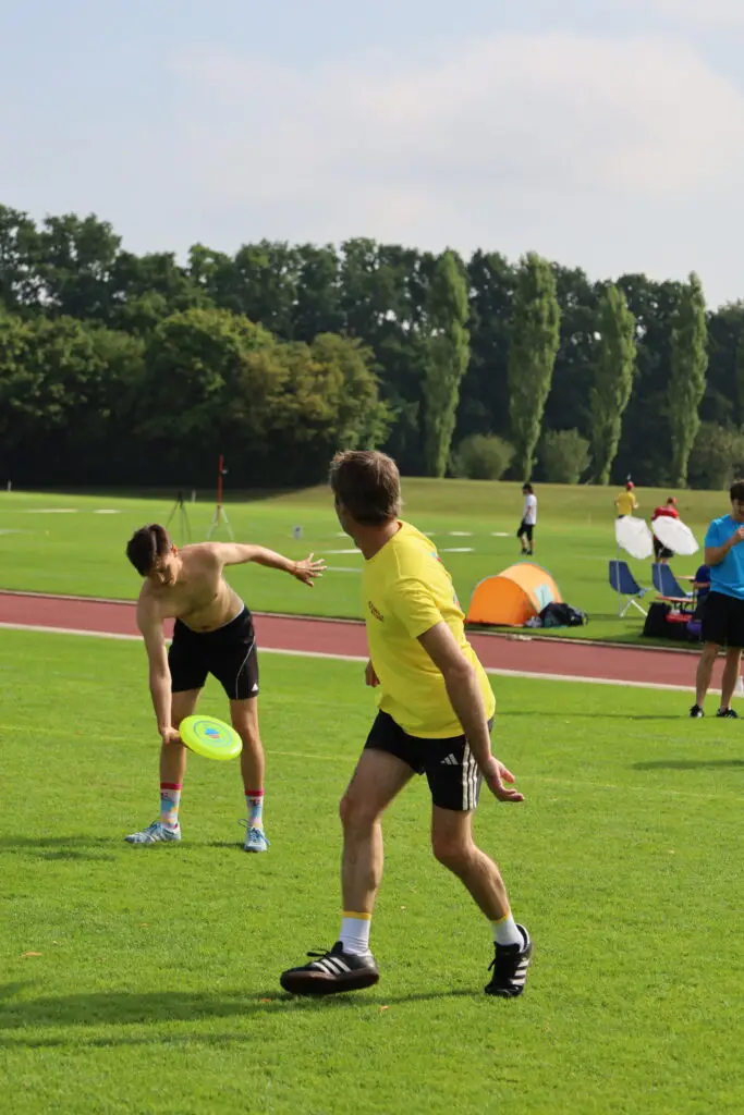 Bildergalerie vom Frisbee Festival M&uuml;nchen an der Sportschule Oberhaching mit Spielszenen auf dem Sportplatz und in der Halle, Turnierst&auml;nden, Zuschauerinnen und Zuschauern sowie verschiedenen Frisbee-Disziplinen wie Disc Golf, Ultimate Frisbee und Freestyle.